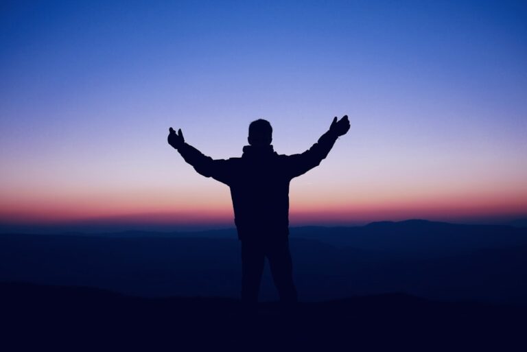 A man standing on top of a hill with his arms outstretched
